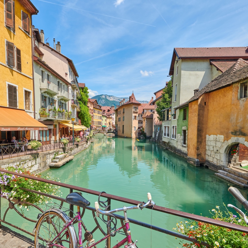 A view of one of Annecy's blue-green canals, with yellow and white buildings on each side of the water